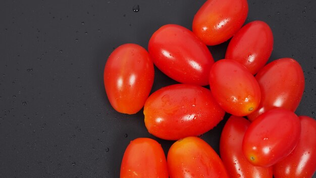 Foto nahaufnahme gruppe von cherry-tomaten auf schwarzem hintergrund.