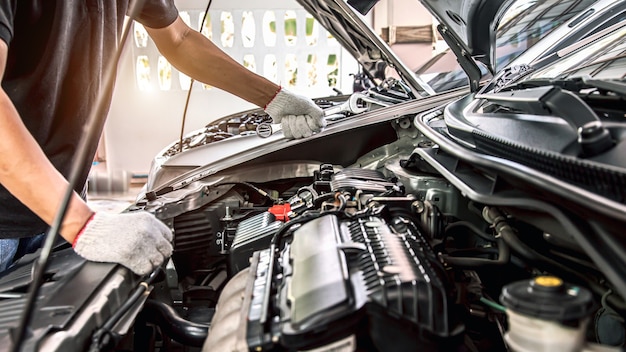 Nahaufnahme hände des automechanikers mit dem schraubenschlüssel zur wartung des automotors.