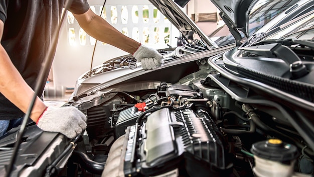 Nahaufnahme Hände des Automechanikers mit dem Schraubenschlüssel zur Wartung des Automotors.