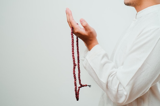 Nahaufnahme Hand, die eine Tasbih- oder Gebetskette auf weißem Hintergrund hält