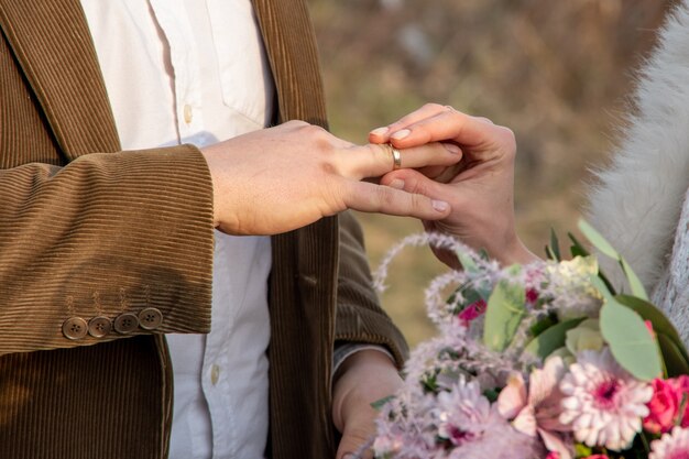 Nahaufnahme Hand einer Braut legt einen Ring auf die Hand eines Mannes. Externe Registrierung