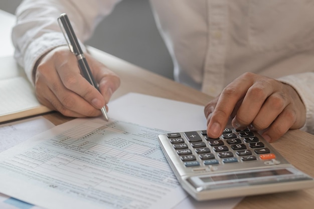 Nahaufnahme Hand Stress junge asiatische Geschäftsmann drückt einen Taschenrechner, um Steuereinnahmen und -ausgaben Rechnungen Kreditkarte für Zahlung oder Zahltag zu Hause zu berechnen Finanzfinanzkonzept