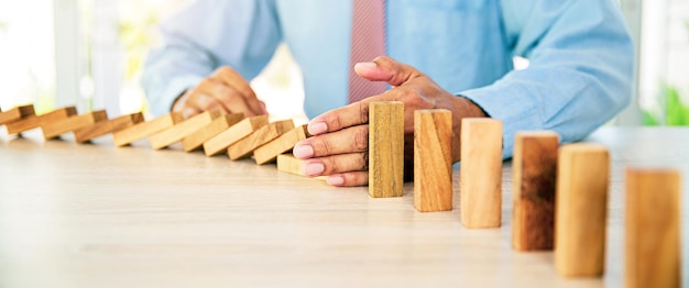 Nahaufnahme Hand verhindern, dass Holzblock nicht fällt Domino-Konzepte des Finanzrisikomanagements und strategische Planung und Business-Herausforderung Plan