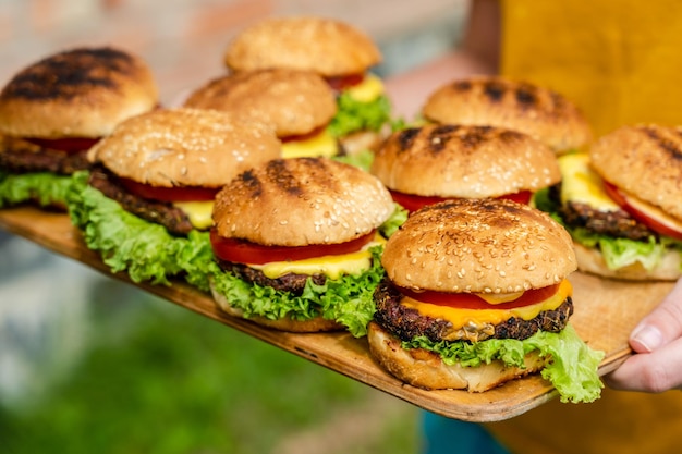 Nahaufnahme hausgemachter Burger aus frischem Gemüse auf Holzplatte mit Frauen