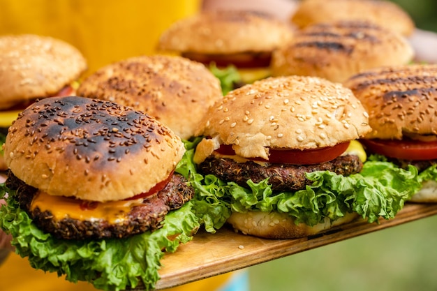 Nahaufnahme hausgemachter Burger aus frischem Gemüse auf Holzplatte mit Frauen