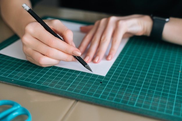 Nahaufnahme hoher Winkel der nicht erkennbaren Designerin, die mit Bleistift auf weißem Leerzeichen markiert