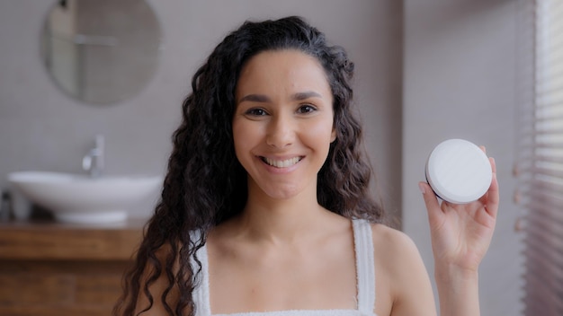 Nahaufnahme junge glückliche hispanische Frau, die im Badezimmer steht und in die lächelnde Werbung der Kamera schaut