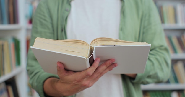 Nahaufnahme junger Mann, der ein Buch in der öffentlichen Bibliothek liest und Seiten umblättert, die Forschung betreiben Selbstbildungskonzept