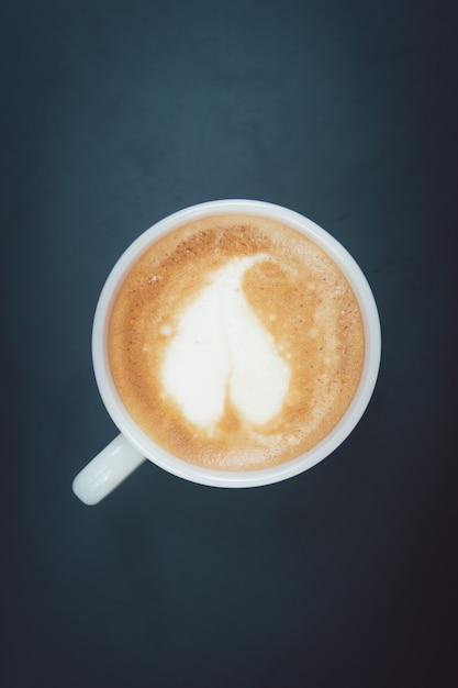 Nahaufnahme Kaffee Latte Kunst in Tasse und Milchschaum oben auf dem schwarzen Tisch am Morgen zu trinken.