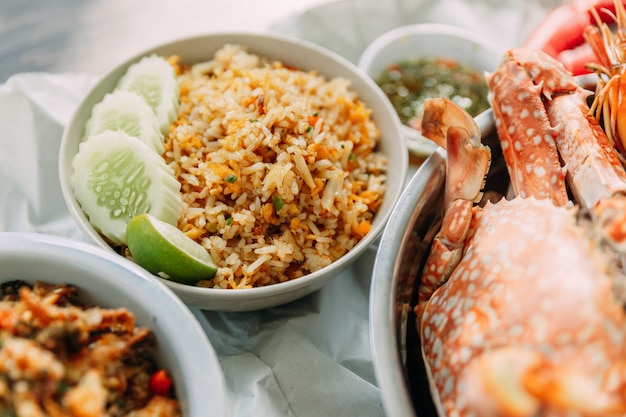 Foto nahaufnahme-krabbe fried rice mit gurke und kalk und gedämpfte blumenkrabben dienten mit würziger meeresfrüchtesoße der thailändischen art.