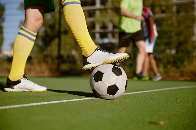 Foto nahaufnahme männlicher fuß in stiefeln auf einem fußball über grünem rasenfeld