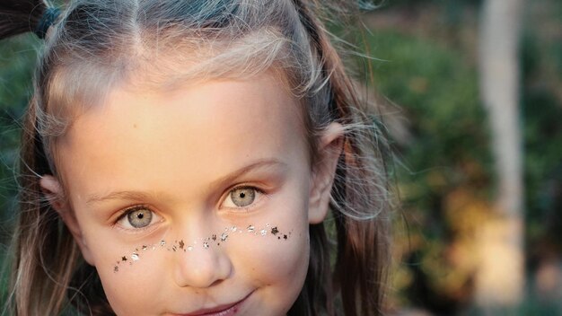 Nahaufnahme-Makroporträt eines lächelnden Mädchengesichtes Kleinkindes, das schöne Kinder-Augen auf die Kamera schaut.