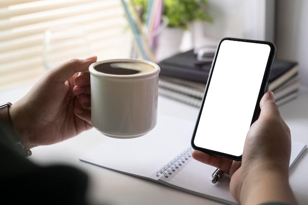 Nahaufnahme Mann Hand mit Tasse Kaffee und mit Handy Leerer Bildschirm für Ihren Werbetext