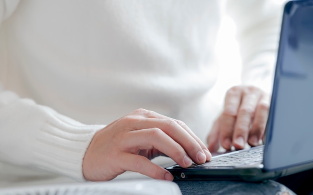 Nahaufnahme Mannhand, die auf Laptop-Tastatur tippt.