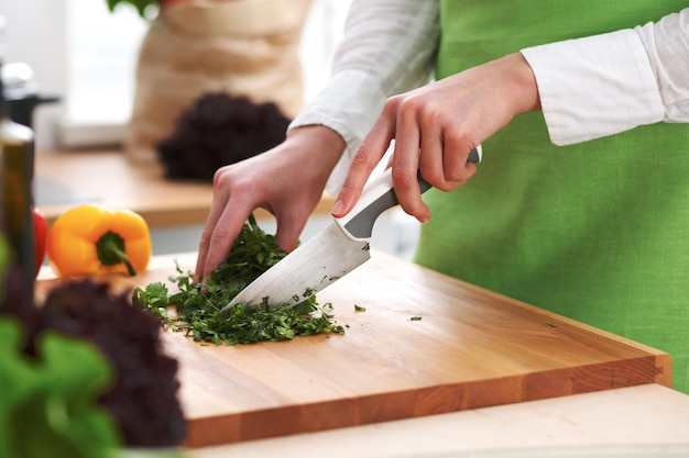 Nahaufnahme menschlicher Hände, die Gemüsesalat in der Küche auf dem Glastisch mit Reflexion kochen. Gesundes Essen und vegetarisches Konzept