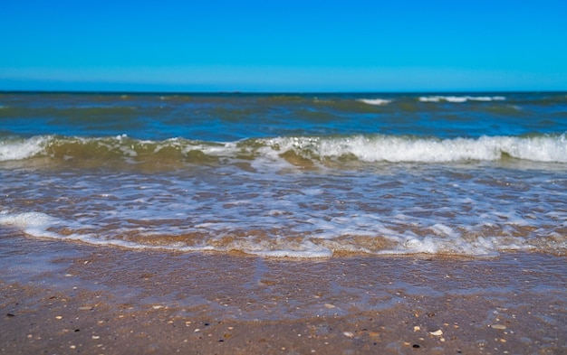 Nahaufnahme mit Wellen von Meer und Sand an einem schönen sonnigen Tag am Strand