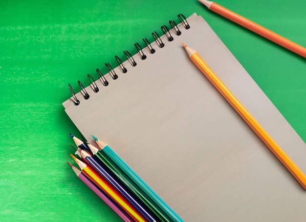 Nahaufnahme-Notizbuch und bunte Bleistifte, grüner Bretthintergrund, generative KI