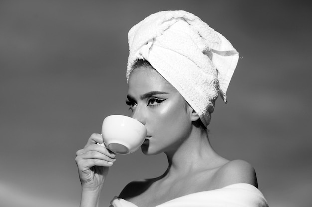 Nahaufnahme Porträt einer Frau, die bei Sonnenaufgang eine Tasse mit Kaffee hält Schönheitsfrau mit Handtuch auf dem Kopf drin