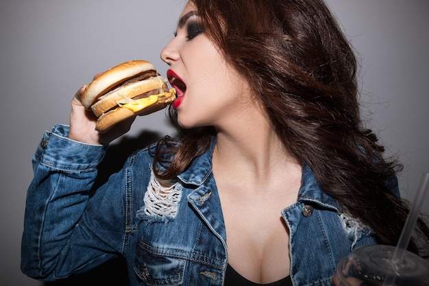 Nahaufnahme Porträt einer Frau, die Burger isst Ungesunde Ernährung von Menschen und Junk-Food-Konzept