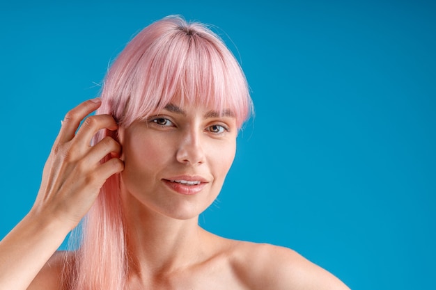 Nahaufnahme Porträt einer sinnlichen Frau mit rosa Haaren und perfekt leuchtender Haut, die in die Kamera schaut