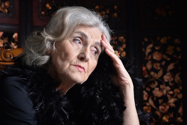 Nahaufnahme Porträt einer traurigen älteren Frau zu Hause mit Telefon