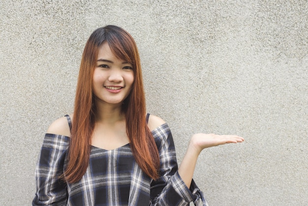 Nahaufnahme Porträt glücklich junge asiatische Frau lächelnd und blinzeln gegen graue Betonmauer. Vintage Tonfilter Farbe Stil.