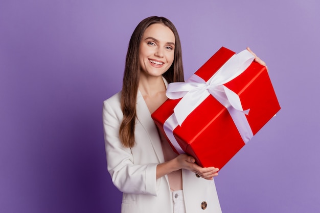 Nahaufnahme Porträt von Dame halten Geschenkbox tragen formellen Anzug posiert auf violetter Wand