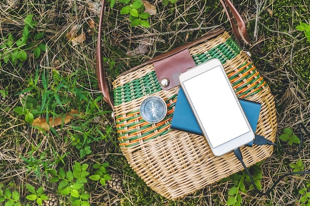 Nahaufnahme, Powerbank mit Mockup-Smartphone auf einem Korb im Wald. Reisekonzept.