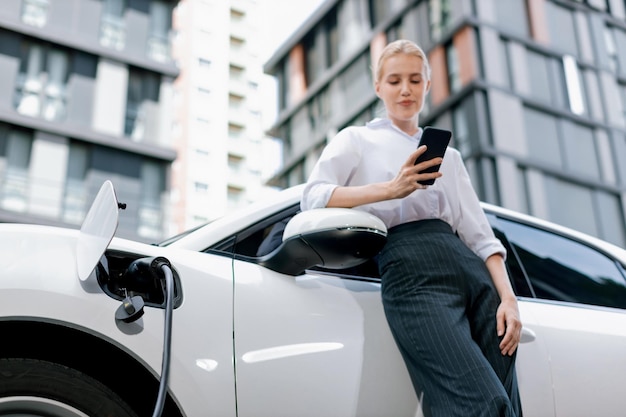 Nahaufnahme progressive Frau, die am Telefon spricht und sich auf ein Elektrofahrzeug stützt