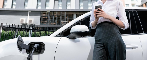 Nahaufnahme progressive Geschäftsfrau mit Elektrofahrzeug an Ladestation