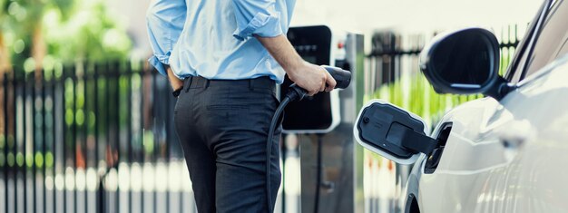 Foto nahaufnahme progressiver geschäftsmann steckt ladestecker von ladestation an ev