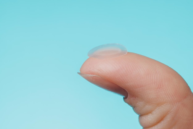 Nahaufnahme runde Aknepflaster auf Finger auf blauem Hintergrund Aknepflaster zur Behandlung von Pickel und Rosazea Nahaufnahme Gesichtsverjüngung Reinigung Kosmetologie
