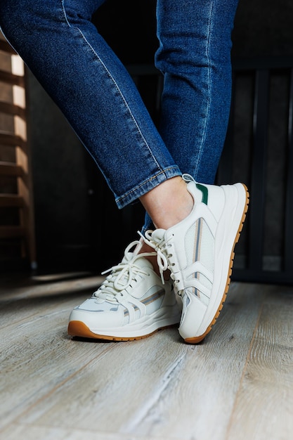 Foto nahaufnahme schlanker weiblicher beine in jeans und weißen turnschuhen aus echtem leder