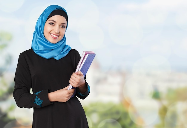 Nahaufnahme schöne junge muslimische Frau mit Notizbuch auf verschwommenem Hintergrund