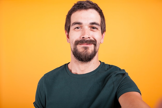 Nahaufnahme Selfie-Porträt eines glücklich lächelnden Mannes isoliert auf gelbem Hintergrund