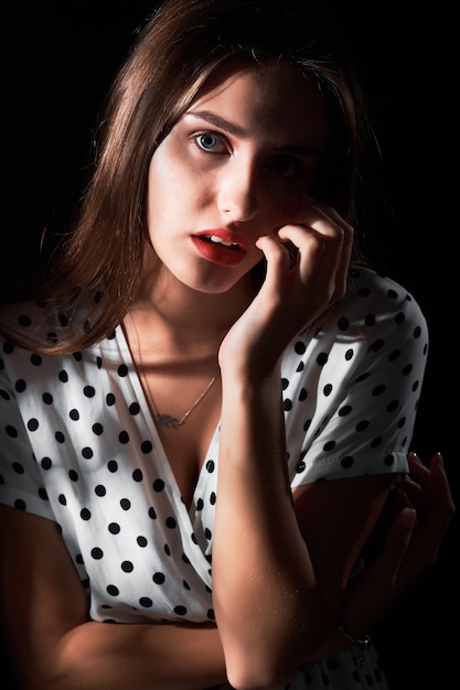 Nahaufnahme-Studioporträt eines jungen Mädchens mit langen Haaren und roten Lippen gegen Schwarz.