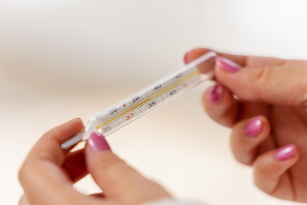 Nahaufnahme Traditionelles Thermometer zur Messung der Körpertemperatur in Frauenhänden