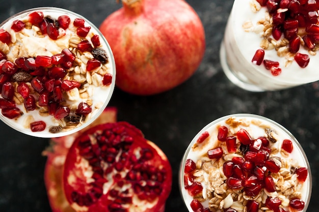 Nahaufnahme über Draufsicht auf Müsli mit Granatapfel auf dunklem Holzhintergrund