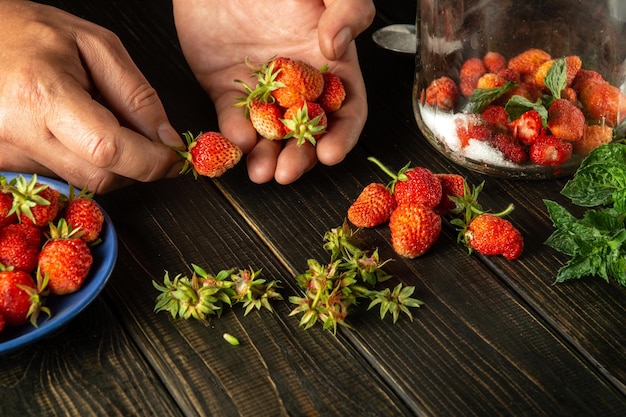 Nahaufnahme übergibt den Koch, der frische Erdbeeren auf dem Schneidebrett der Restaurantküche sortiert