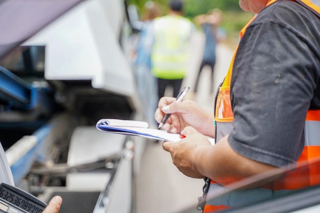 Nahaufnahme und Ernteversicherungsagent, der in die Zwischenablage schreibt, während er das Auto nach einem Unfallschaden untersucht