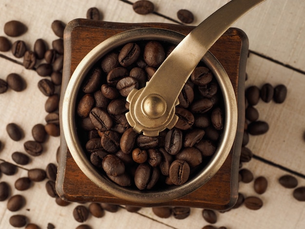 Nahaufnahme Vintage Kaffeemühle Mühle mit Kaffeekörnern auf einem dunklen und hellen hölzernen Hintergrund.