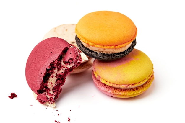 Nahaufnahme von 4 bunten Macarons, rosa, rot, orange und cremebraun, Halfbitten-rote Macarons, isoliert auf weißem Hintergrund