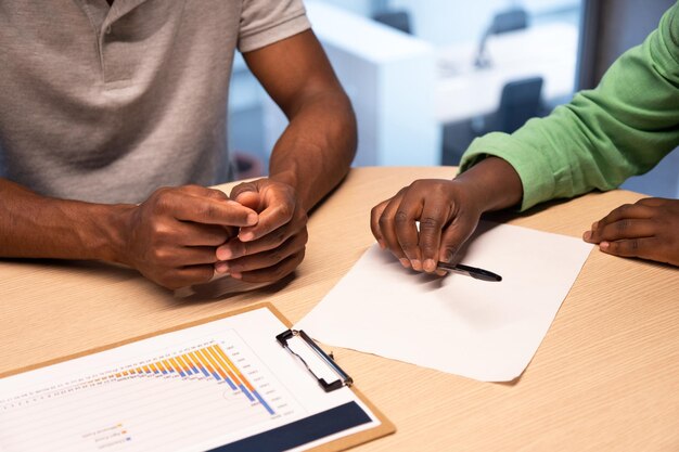 Nahaufnahme von Afroamerikanern, die einen Vertrag im Büro unterzeichnen. Geschäftskonzept.