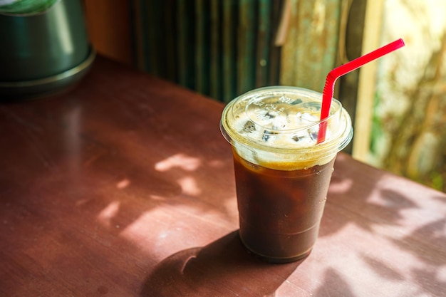 Nahaufnahme von Americano-Eiskaffee oder schwarzem Kaffee in der Tasse auf dem Schreibtisch aus Glasholz im Café im Café im Garten während des Geschäftsarbeitskonzepts