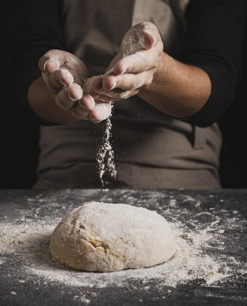 Nahaufnahme von Bäckerhänden, die Mehl streuen, hochwertige schöne Foto-Konzept