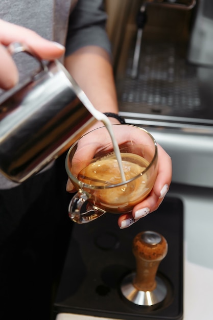 Nahaufnahme von Barista, der Milch in Kunst-Cappuccino oder Latte gießt.