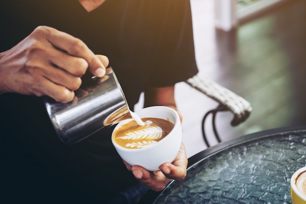 Nahaufnahme von barista Lattekunstfokus in der Milch und im Kaffee in der Weinlesefarbe machen Selektiver Fokus