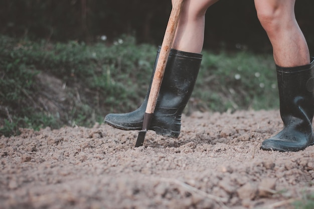 Nahaufnahme von Beinabnutzung, die Stiefel graben den Boden, bereiten sich auf Pflanzengemüse vor