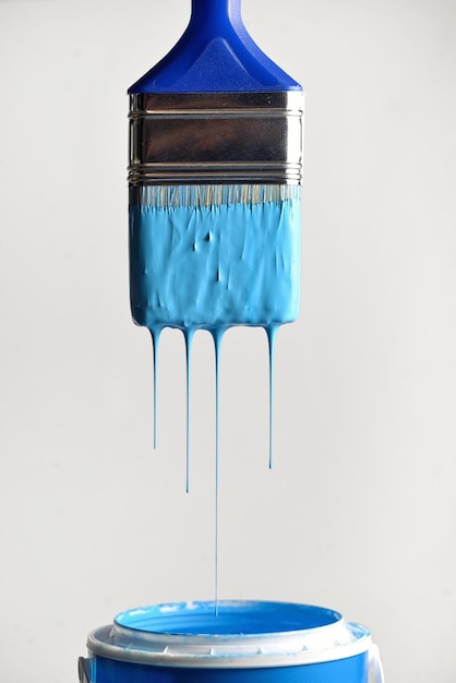 Nahaufnahme von blauer Farbe, die in den Behälter gegen die Wand tropft
