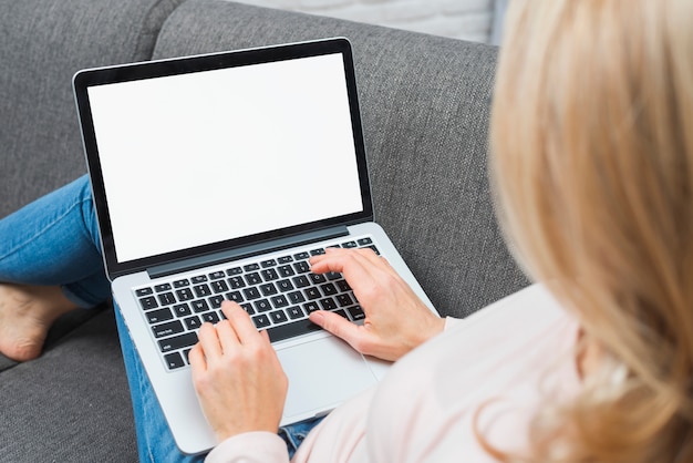 Nahaufnahme von Blondinen sitzend auf Sofa unter Verwendung des Laptops mit leerem weißem Bildschirm